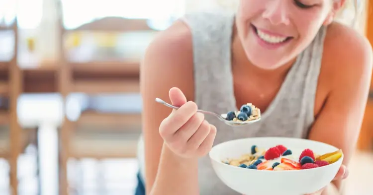 una ragazza che fa colazione sorridente con i mirtilli | Dimann